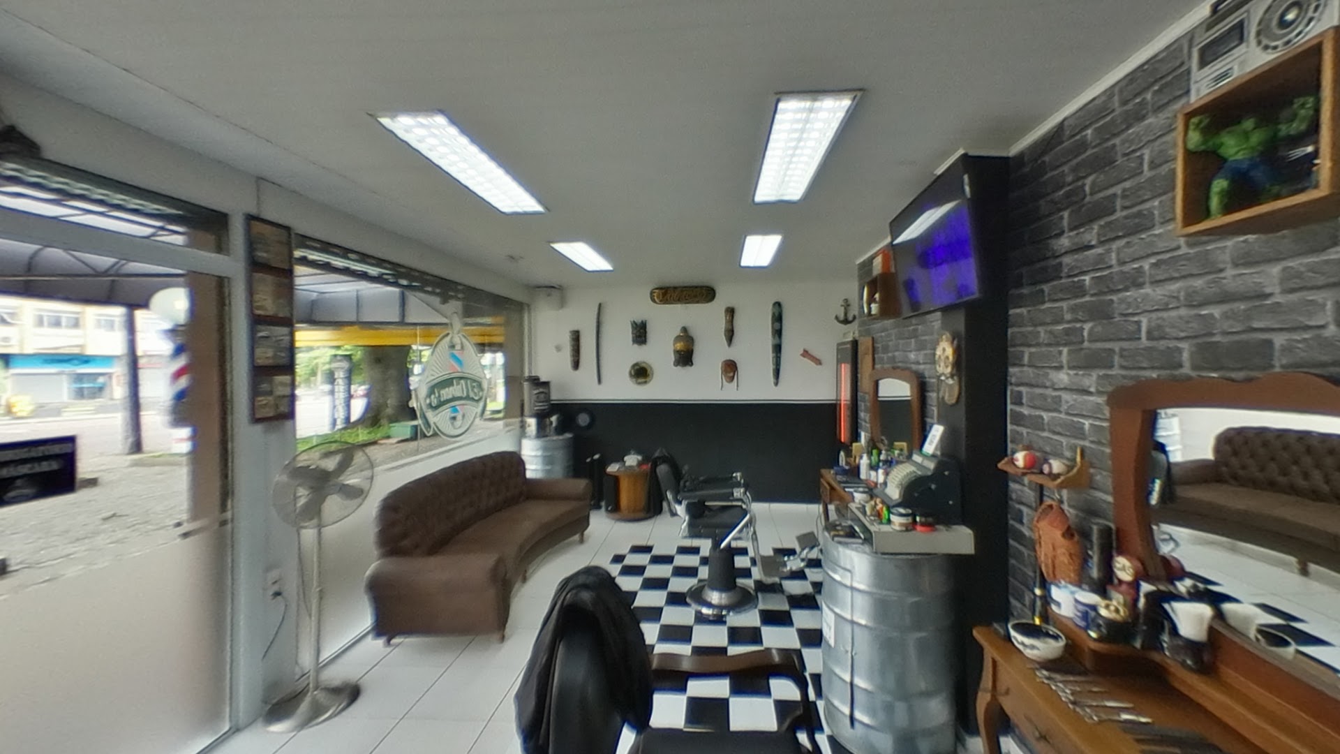 Sofá e cadeiras de barbeiro dentro do salão da Barbearia El Cabron's